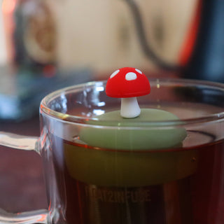 Glass mug with a red and white mushroom-shaped lid on a blurred background