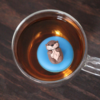 Clear mug with a cartoon otter on a blue circle in a cup of tea