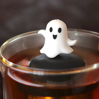 Ghost-shaped object floating in a glass of tea with a dark background