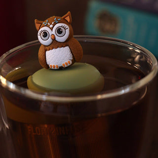 Owl-shaped object on a green sphere inside a glass of liquid
